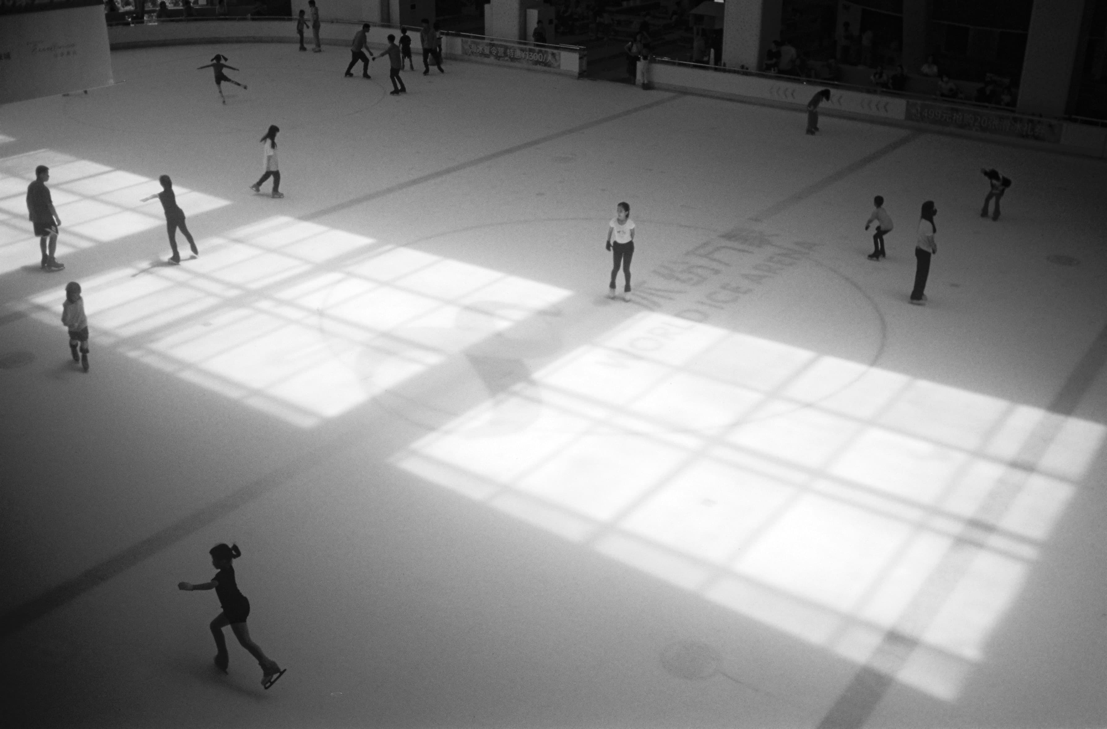 Figures crossing a sunlit interior in black and white