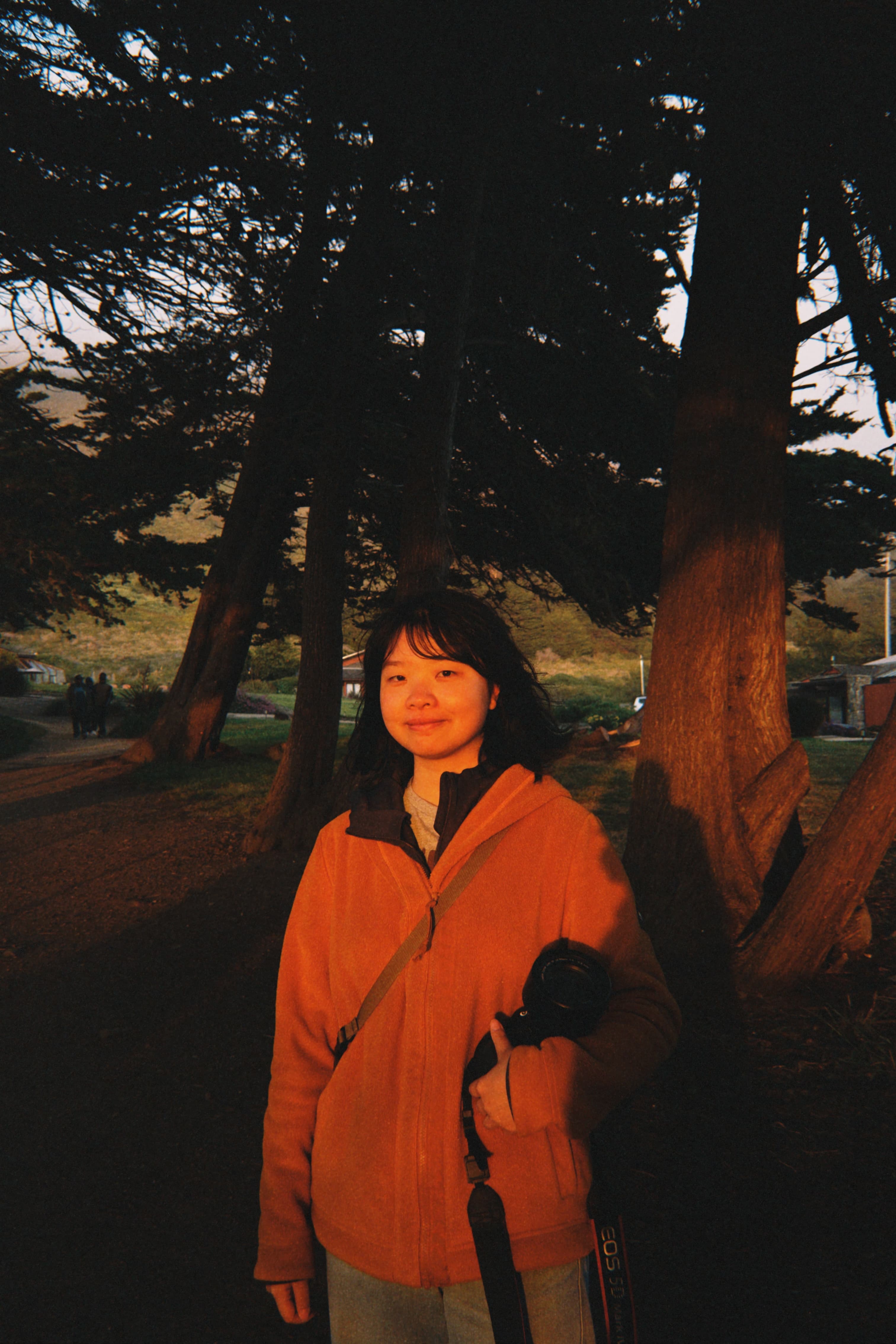Yueshan Jiang standing among trees with a camera