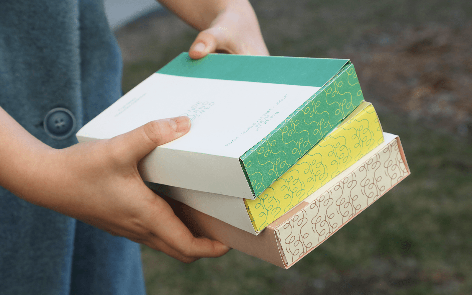 A person holding three stacked chocolate collection boxes outdoors