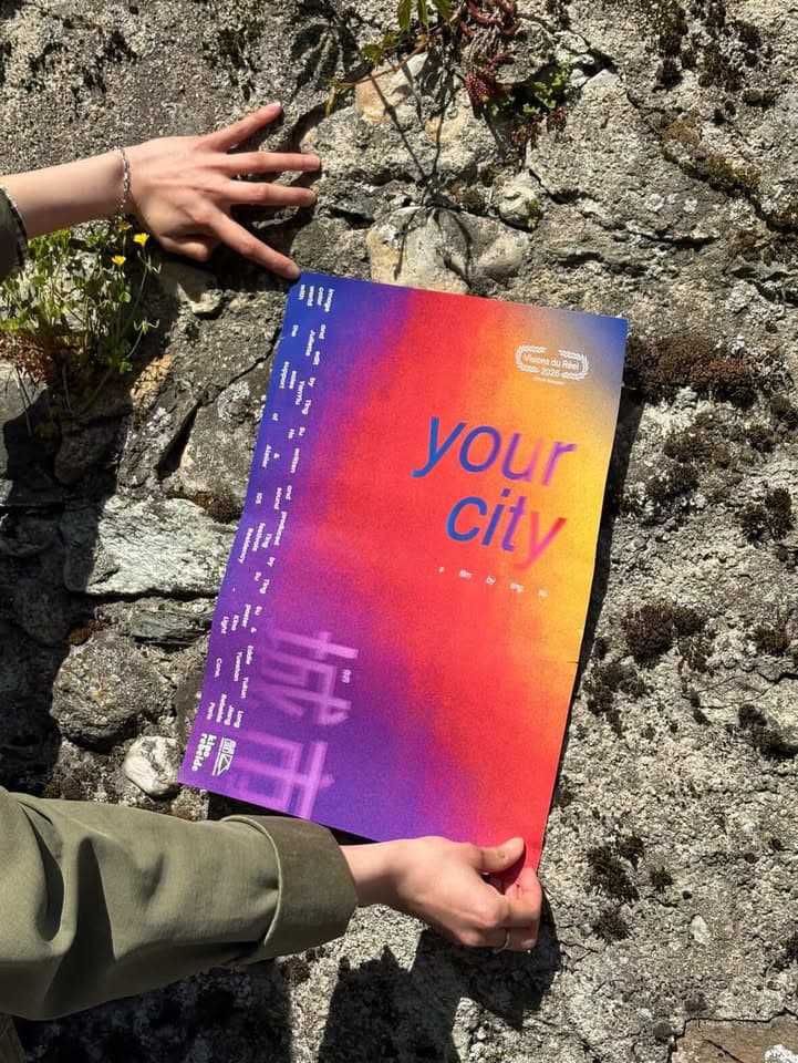 A person holding the Your City poster outdoors